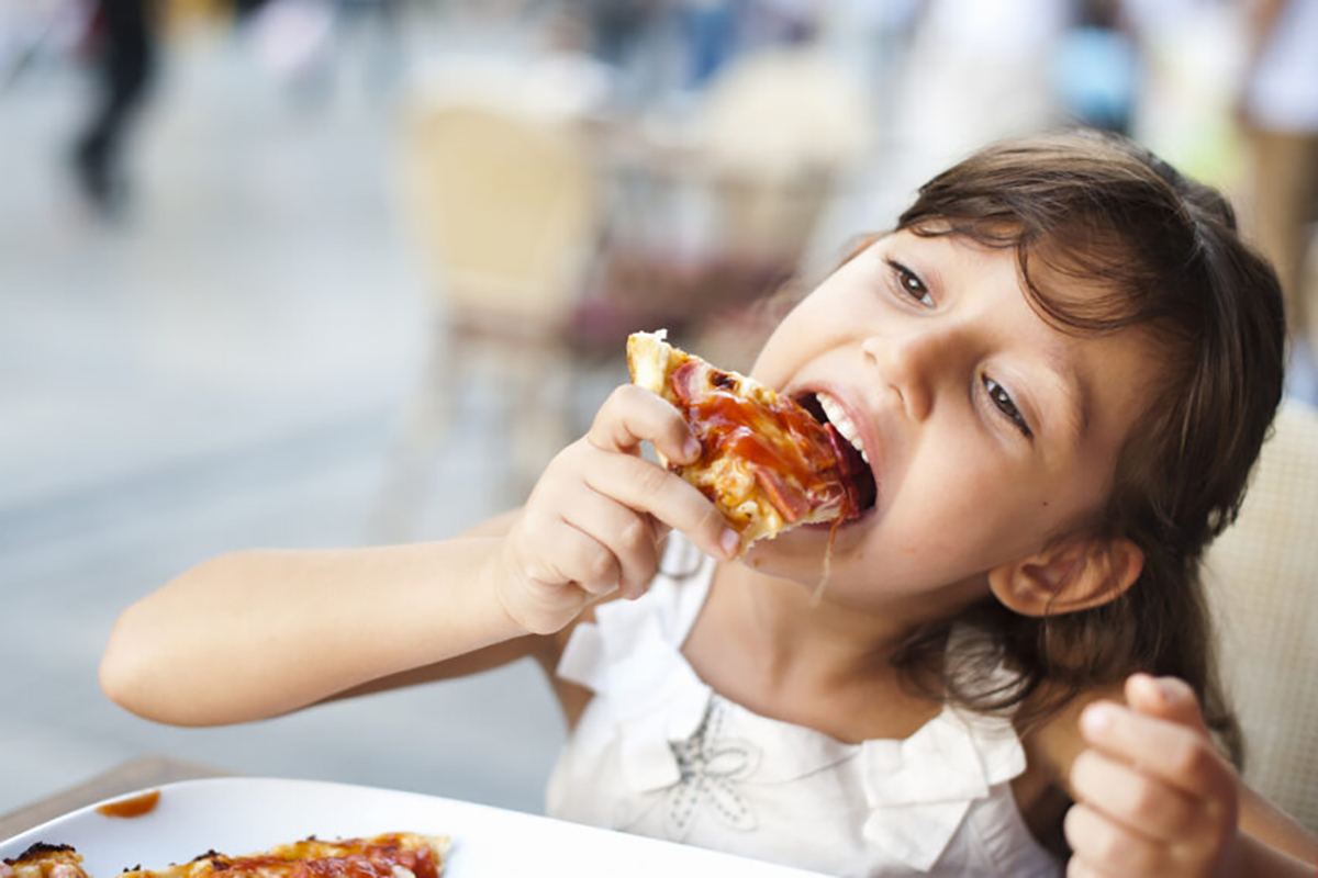 Bambina che mangia pizza (foto d'archivio)